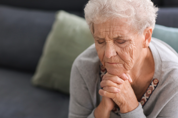 Elderly woman sitting on a couch worried