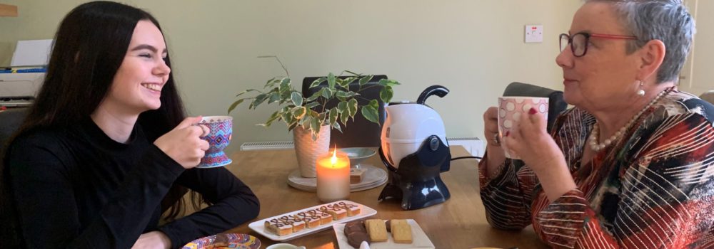 Granddaughter and grandmother sharing a conversation over a cup of tea