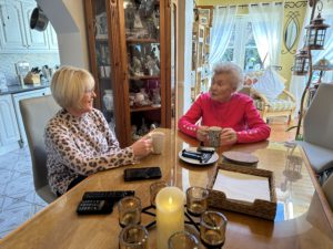 Elderly woman sitting at the dining room table with her daughter talking and drinking tea