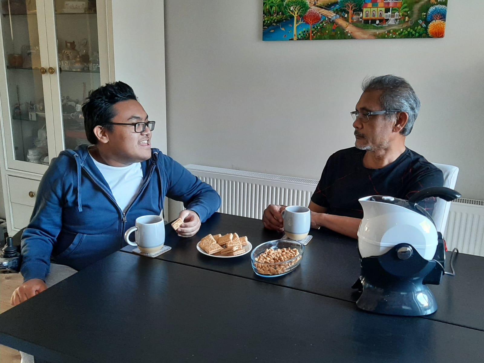 Father and son enjoying tea and biscuits in the dining room